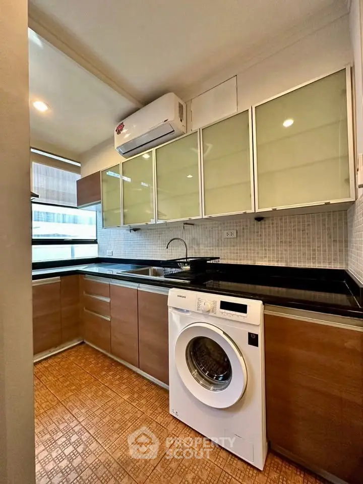 Modern kitchen with washing machine and sleek cabinetry in a cozy apartment.