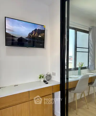 Modern interior with wall-mounted TV and dining area with natural light.