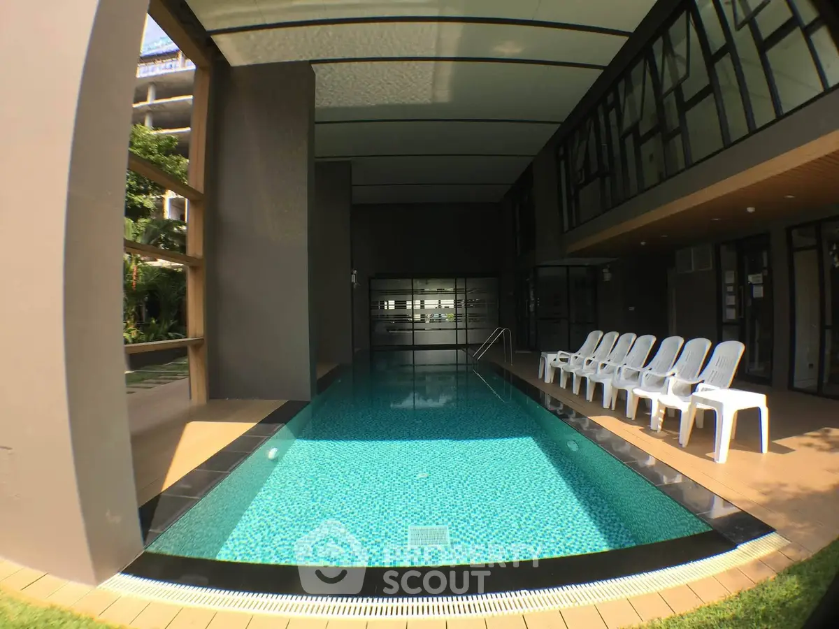 Luxurious indoor pool area with modern design and ample seating in a high-end residential building.