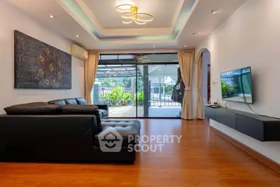 Spacious living room with modern decor and large glass doors leading to a balcony with garden view.