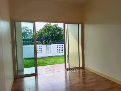 Bright room with sliding glass doors opening to a lush garden view, perfect for relaxation.