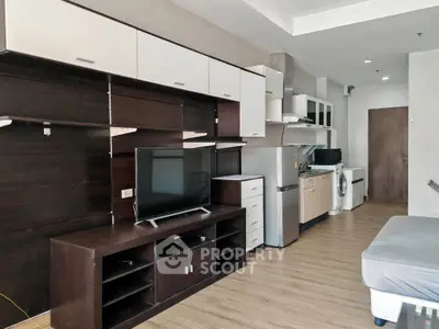 Modern studio apartment with sleek kitchen and entertainment area, featuring a washing machine and flat-screen TV.
