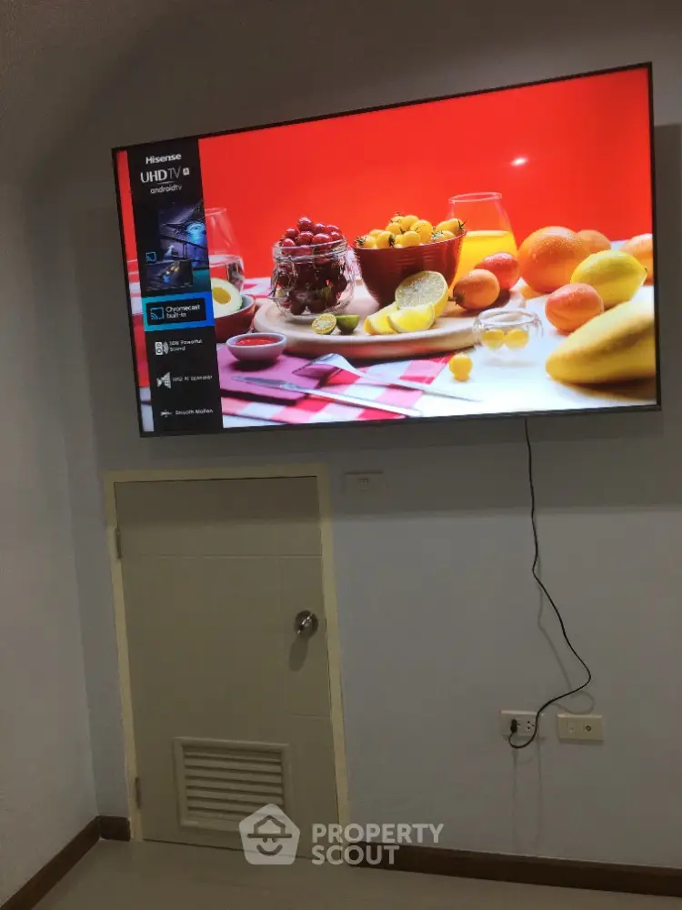 Modern living room with wall-mounted UHD TV and vibrant fruit display