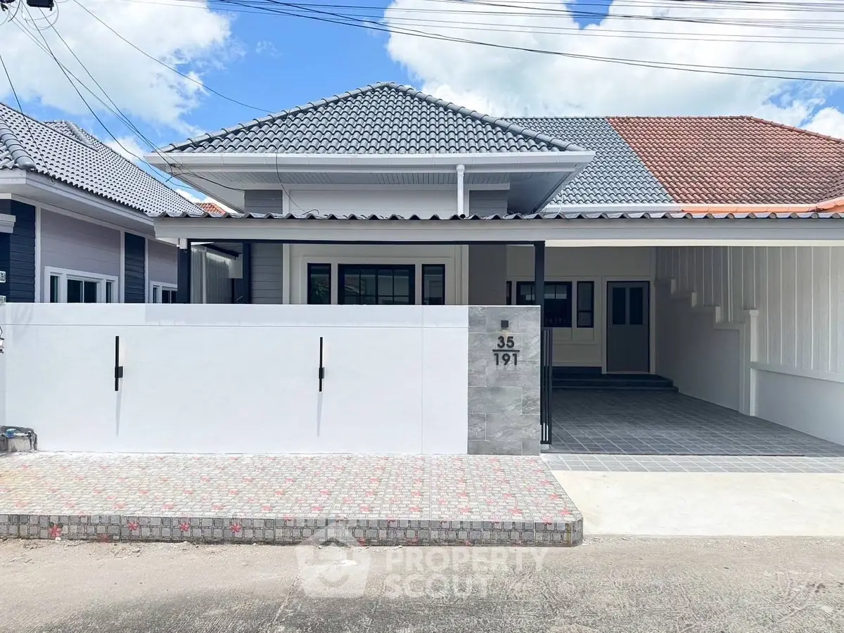 Charming single-story house with modern roof design and spacious driveway.