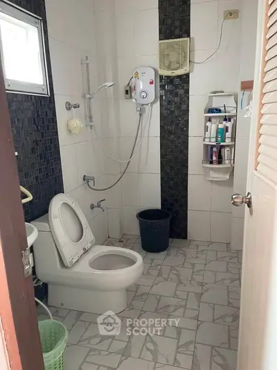 Compact bathroom with modern shower and tiled flooring, featuring essential amenities for convenience.