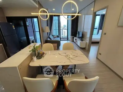 Modern open-plan living and dining area with city view, stylish lighting, and elegant furnishings.