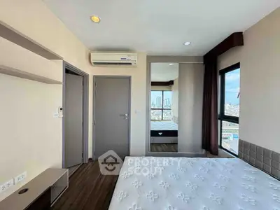 Modern bedroom with city view, featuring a large mirror and air conditioning.
