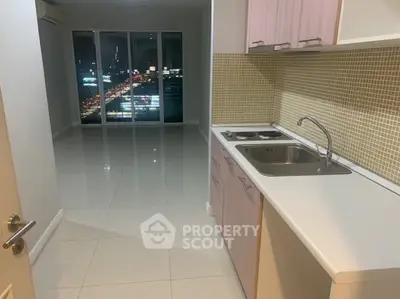 Modern apartment with sleek kitchen and stunning city view at night.