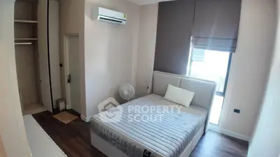 Modern bedroom with air conditioning and natural light, featuring a comfortable bed and built-in closet.