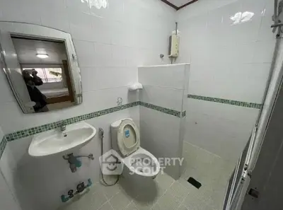 Modern bathroom with white tiles and compact design, featuring a wall-mounted sink and toilet.