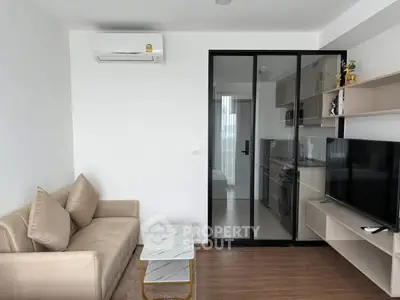 Modern living room with sleek design and glass partition leading to kitchen
