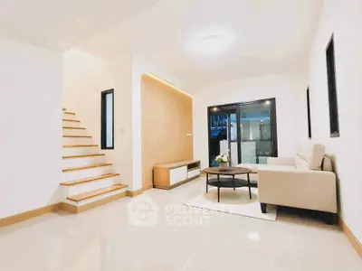 Modern living room with sleek staircase and cozy seating area, perfect for relaxation and entertaining.