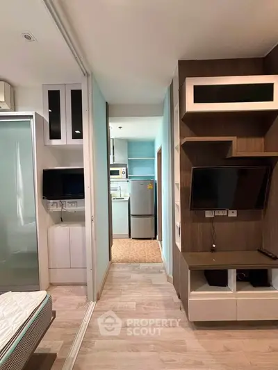 Modern apartment interior with open layout, featuring a cozy living area and sleek kitchen appliances.