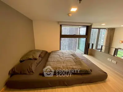Modern bedroom with large windows and city view, featuring minimalist design and cozy bedding.