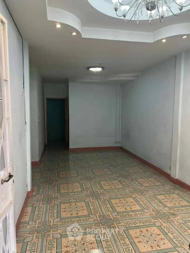 Spacious empty room with decorative tiled floor and chandelier lighting