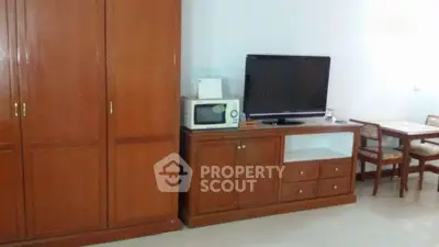 Spacious living area with wooden furniture and modern appliances for comfortable living.