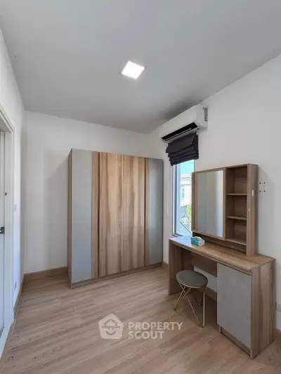 Modern bedroom with wooden wardrobe and vanity set, featuring sleek design and ample natural light.