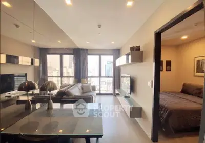 Modern apartment with open living room and bedroom, featuring sleek furniture and city view.