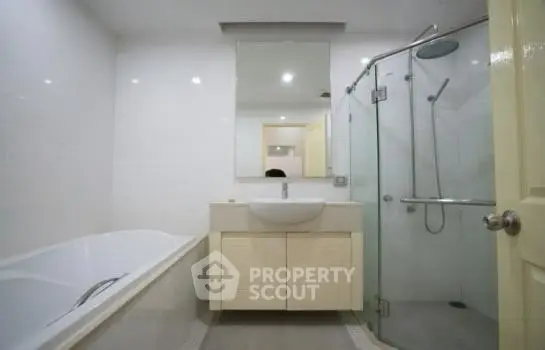 Modern bathroom with glass shower and bathtub in sleek design.