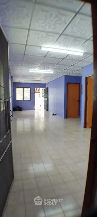 Spacious interior with tiled flooring and vibrant blue walls, ideal for versatile living arrangements.