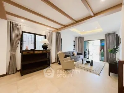 Spacious living room with elegant decor and natural light, featuring modern furniture and stylish ceiling beams.