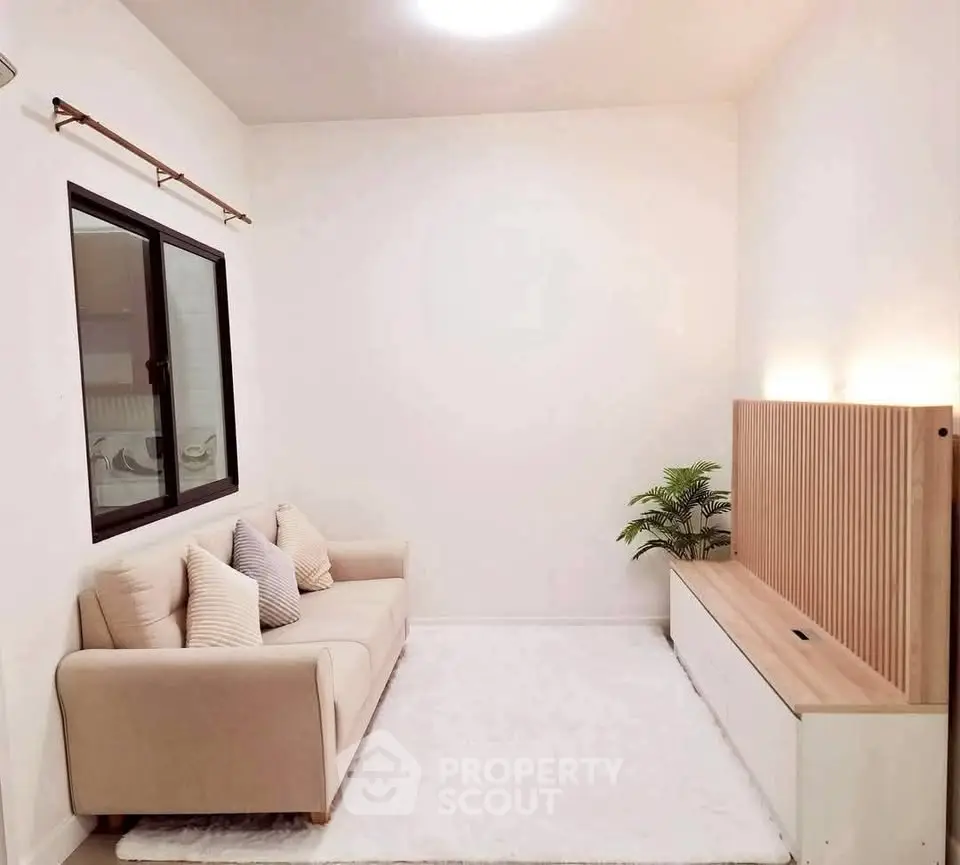 Cozy minimalist living room with beige sofa and modern wooden panel decor.