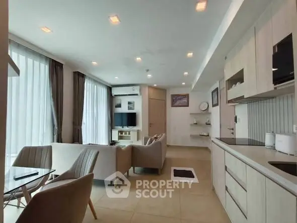 Modern open-plan living room with sleek kitchen and large windows in a stylish apartment.
