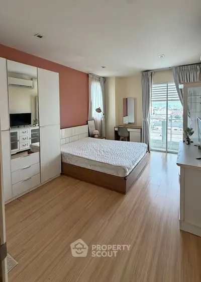 Spacious bedroom with modern decor and large windows offering city views.