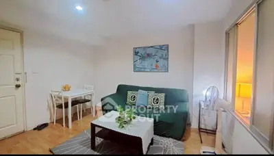 Cozy living room with green sofa and dining area, perfect for relaxation.