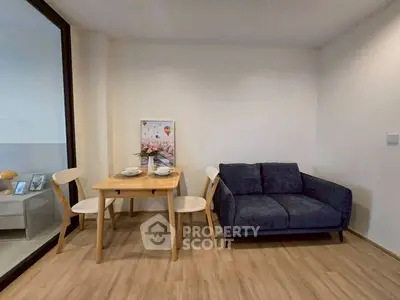 Cozy dining area with a small table and chairs next to a comfortable sofa in a modern apartment.