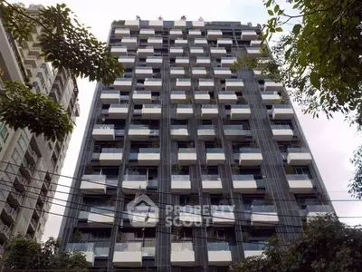 Modern high-rise building with unique balcony design and lush greenery.