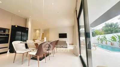 Luxurious open-plan living room with pool view, modern dining area, and sleek kitchen appliances.