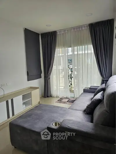 Modern living room with large windows and stylish gray sofa, perfect for relaxation and entertainment.