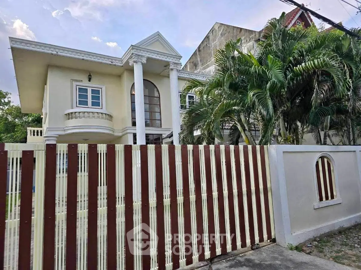 Elegant two-story house with columns and lush palm trees