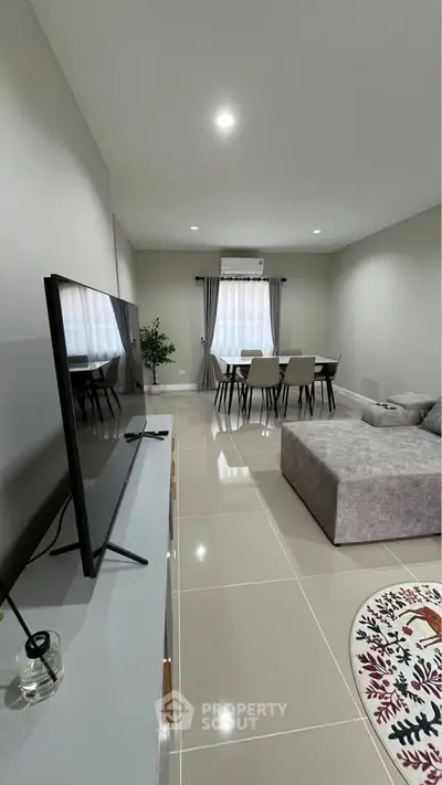 Modern living room with sleek TV setup and cozy dining area, perfect for contemporary living.