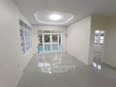 Spacious living room with large windows and glossy tiled flooring