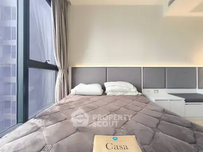 Modern bedroom with large window and stylish decor in urban apartment.