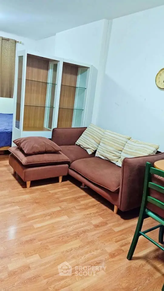 Cozy living room with brown sofa and wooden flooring, perfect for relaxation.