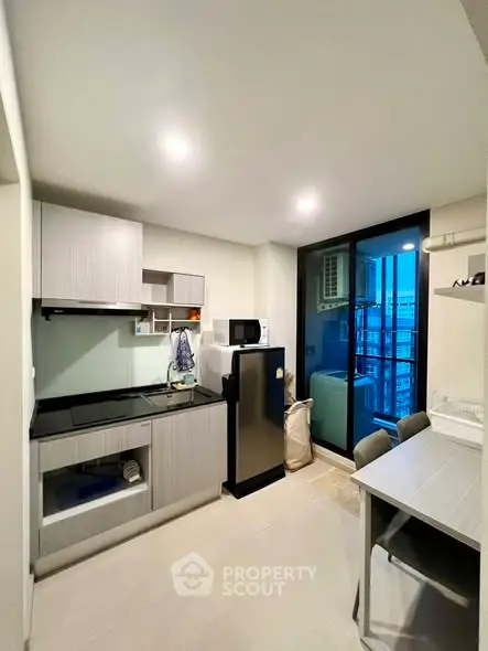 Modern kitchen with sleek appliances and balcony view in a stylish apartment.