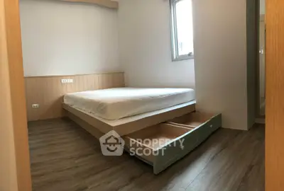 Cozy bedroom with wooden flooring and under-bed storage in modern apartment.