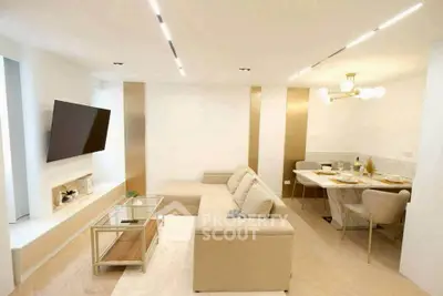 Modern living room with beige sectional sofa, wall-mounted TV, and elegant dining area.
