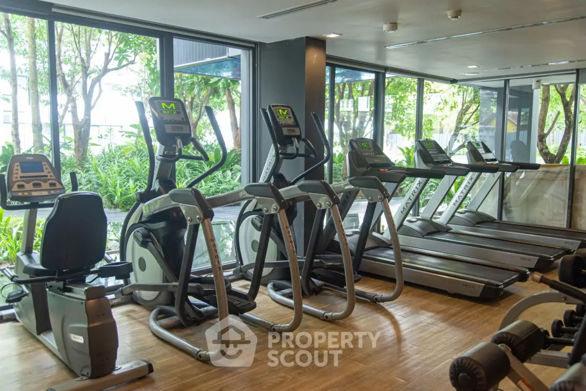 Modern gym with state-of-the-art equipment and large windows overlooking lush greenery.