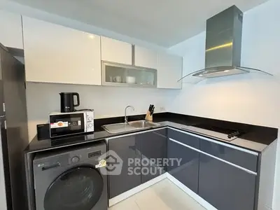 Modern kitchen with sleek cabinetry, washing machine, and built-in appliances in a stylish corner layout.