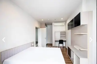 Spacious modern bedroom with study area and sleek furnishings in a bright apartment.