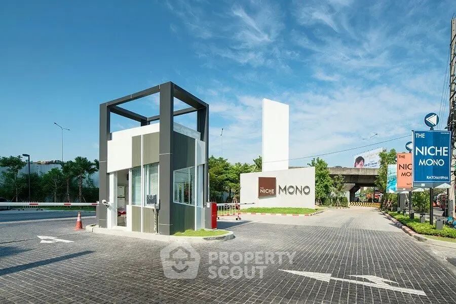 Modern entrance of Niche Mono condominium with sleek design and clear blue sky.