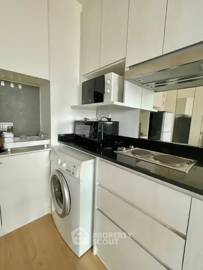 Modern kitchen with sleek appliances and washing machine in compact layout