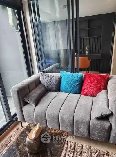 Modern living room with stylish sofa and colorful cushions, featuring floor-to-ceiling windows and a cozy atmosphere.