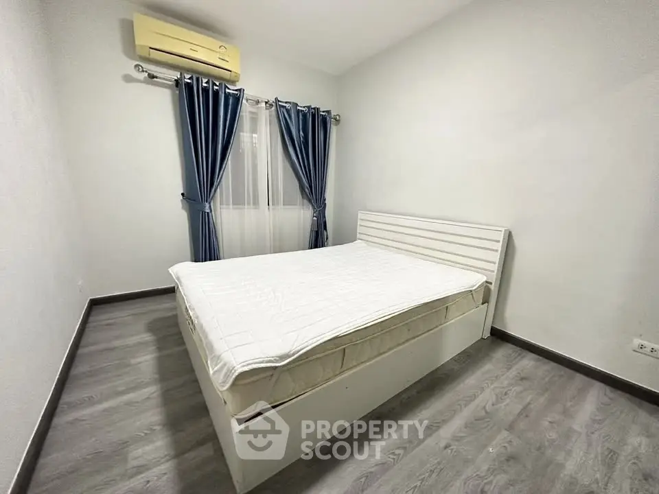 Spacious bedroom with modern decor and air conditioning, featuring elegant blue curtains and sleek flooring.