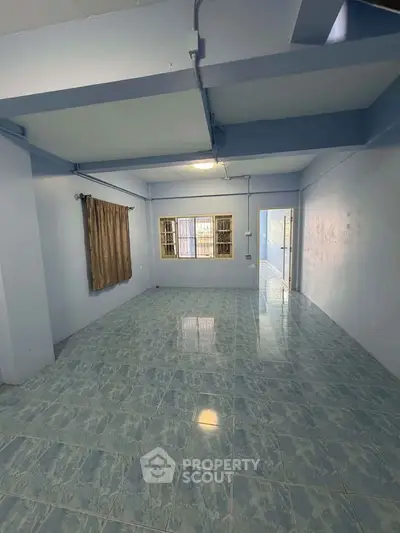 Spacious empty room with tiled floor and large window, ideal for customization.