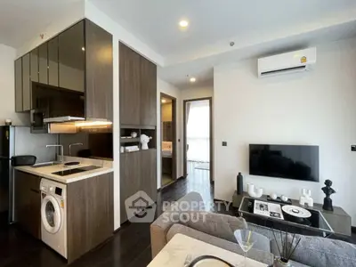 Modern living room with integrated kitchen and washing machine, featuring sleek design and contemporary decor.